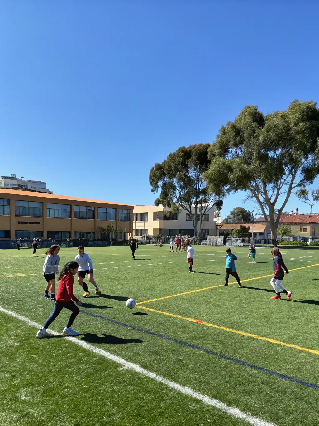 A group of students playing soccer on a sunny field, wearing ASSOCIATION SPORTIVE ET CULTURELLE LA SAULE jerseys, showcasing teamwork and sportsmanship.